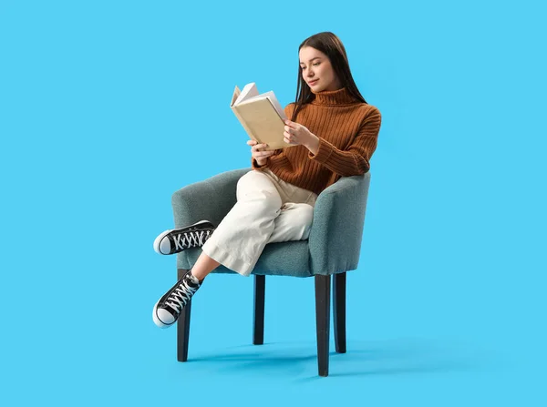 Νεαρή Γυναίκα Διαβάζει Βιβλίο Στην Πολυθρόνα Μπλε Φόντο — Φωτογραφία Αρχείου