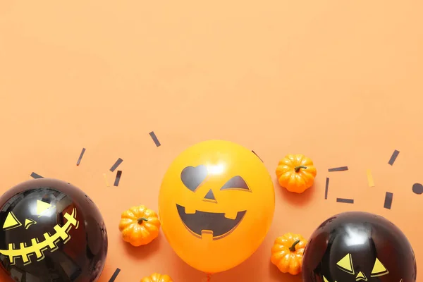 Halloween balloons, pumpkins and confetti on color background