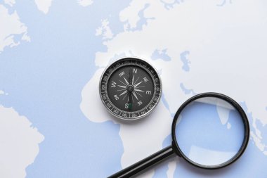 Dünya haritasında büyüteç ve klasik pusula