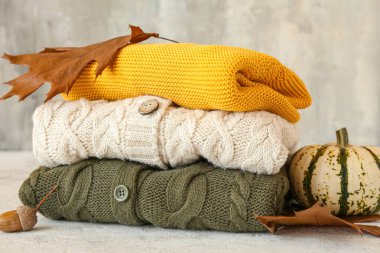 Farklı çocuk süveteri yığını ve arka planda sonbahar dekoru