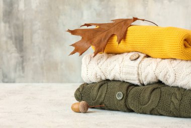 Hafif arka planda farklı çocuk süveteri, meşe palamudu ve sonbahar yaprakları yığını