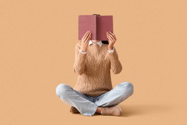 Bej arka plan üzerine kitap okuyan genç bir kadın.