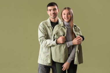 Yeşil arka planda sonbahar kıyafetleri içinde şık genç bir çift.