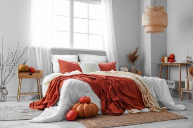 Büyük yataklı, masalı ve balkabaklı aydınlık yatak odasının içi.