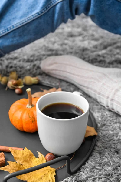 Tray with cup of delicious pumpkin coffee and autumn decor on soft plaid, closeup