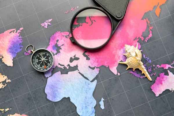 Compass, magnifier and seashell on world map