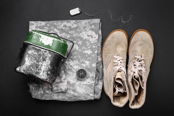 Military uniform, shoes, compass, tag and bowler on dark background