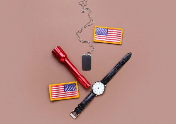 Chevrons of USA army, military tag, flashlight and wristwatch on color background