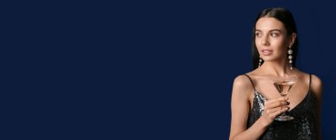 Koyu mavi arka planda martini içen genç ve güzel bir kadın.