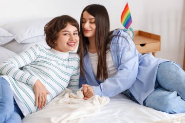 Genç hamile bir kadın ve karısı evde yatakta yatıyor.