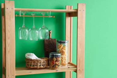 Ahşap raf ünitesi. Yiyecek, yiyecek ve bardaklar yeşil duvarın yanında.