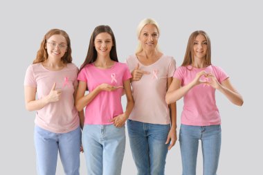 Açık arkaplanda pembe farkındalık kurdeleleri olan güzel kadınlar. Göğüs kanseri kavramı