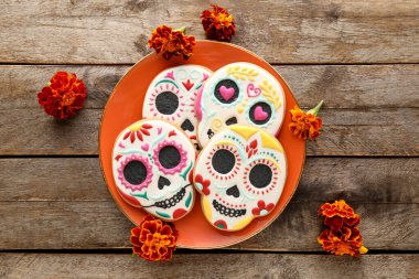 Kafatası şeklinde kurabiyeler ve ahşap arka planda çiçekler. El Dia de Muertos