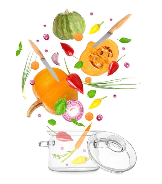 Flying fresh vegetables with knives and glass saucepot on white background