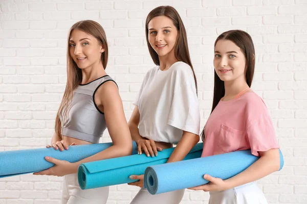 Sportliche Junge Frauen Mit Yogamatten Auf Weißem Backsteinhintergrund — Stockfoto