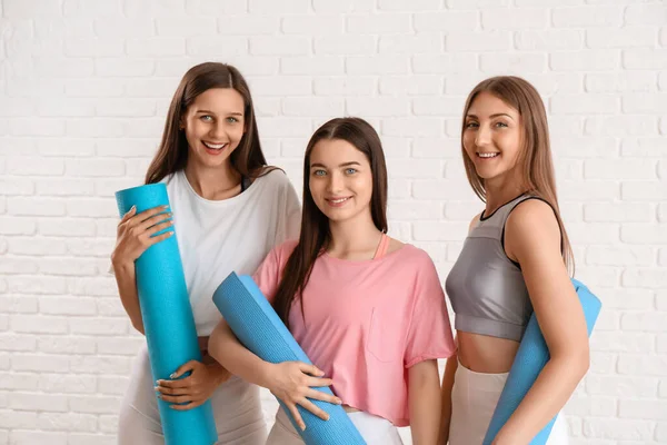 Sportliche Junge Frauen Mit Yogamatten Auf Weißem Backsteinhintergrund — Stockfoto