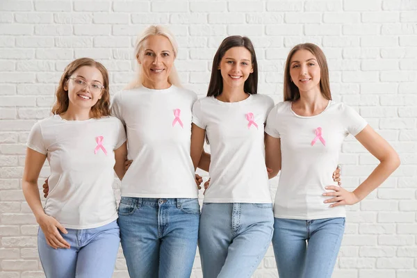 ピンクの意識のリボンが白いレンガの背景に抱きつく美しい女性 乳がんの概念 — ストック写真