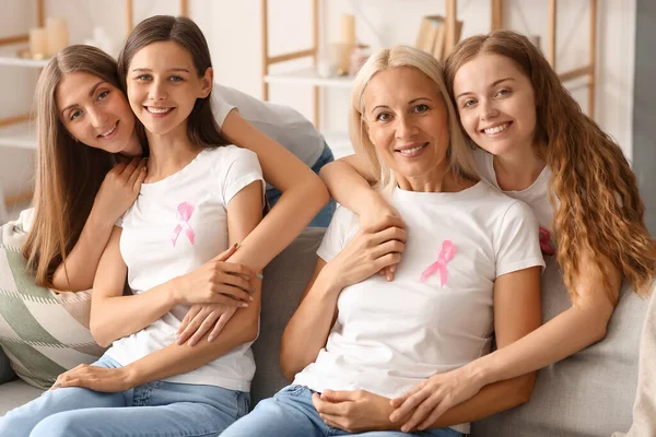 Mulheres Bonitas Com Fitas Consciência Rosa Abraçando Sofá Casa Conceito — Fotografia de Stock