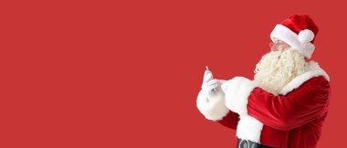 Kırmızı arka planda cep telefonu olan Noel Baba 'nın portresi