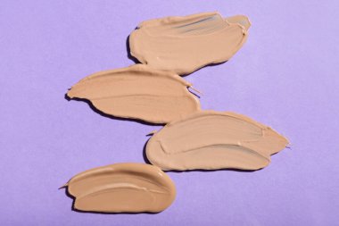 Mor arkaplanda makyaj malzemesi izleri