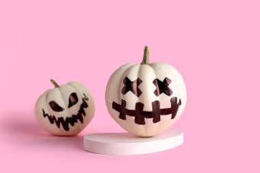 Pembe arka planda yüzleri çizilmiş Cadılar Bayramı balkabakları