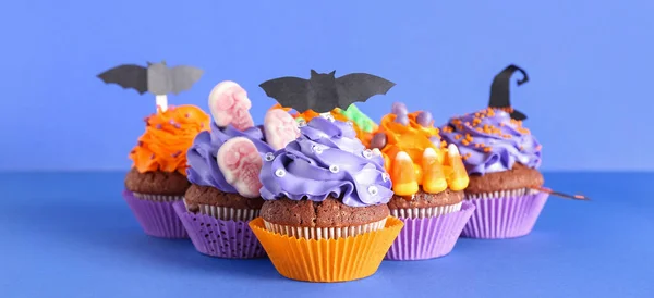 Tasty Halloween cupcakes on blue background