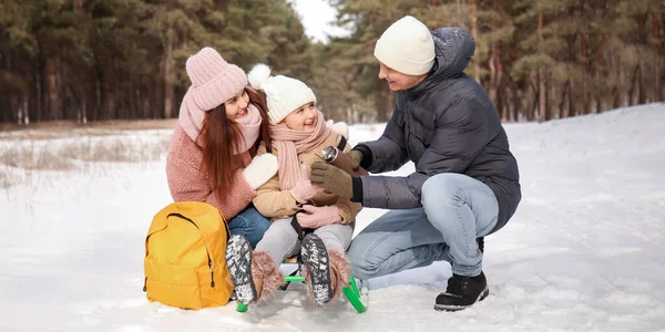 Happy young family drinking hot tea in park on winter day