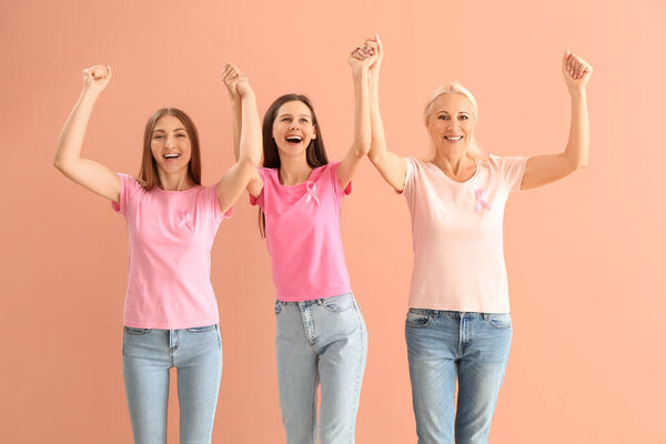 Happy women with pink awareness ribbons on color background. Breast cancer concept