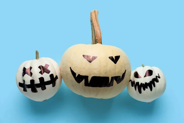 Halloween pumpkins with drawn faces on color background