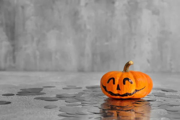 Halloween pumpkin with drawn face and confetti on grunge background