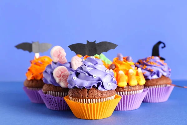 Tasty Halloween cupcakes on blue background