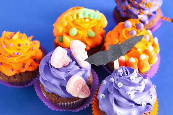 Tasty Halloween cupcakes on blue background, closeup