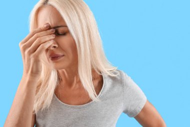 Stresli olgun kadın mavi arka planda, yakın plan