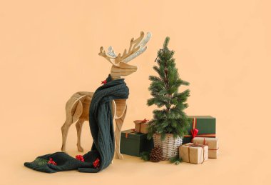 Eşarplı ahşap ren geyiği, Noel ağacı ve bej arka planda hediyeler