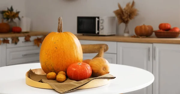 Tray with fresh pumpkins on dining table in kitchen