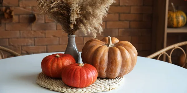 Halloween pumpkins and vase with floral decor on dining table in kitchen