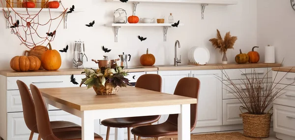 Interior of modern kitchen decorated for Halloween with dining table