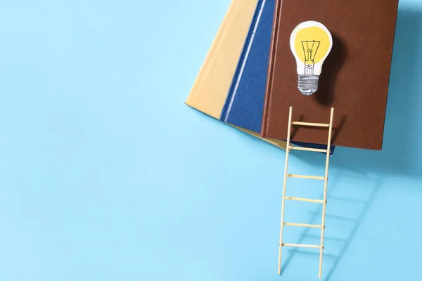 Ladder, books and light bulb on color background