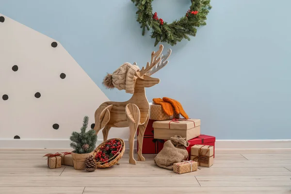 クリスマスツリーと色の壁の近くにプレゼントを持つ木製のトナカイ — ストック写真