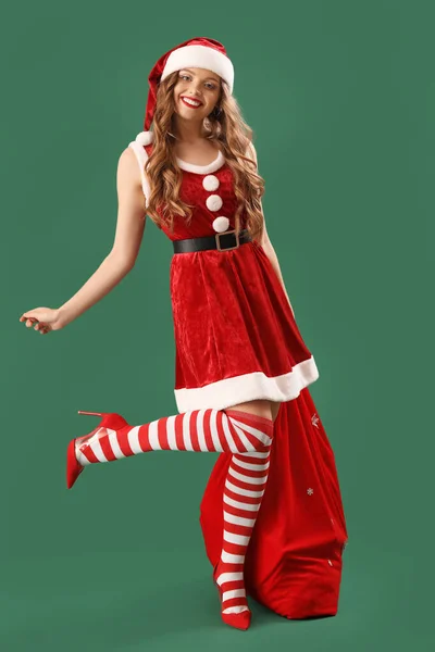 Hübsche Junge Frau Weihnachtsmannkostüm Mit Tasche Auf Grünem Hintergrund — Stockfoto