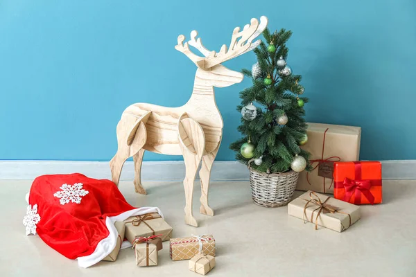 サンタバッグ クリスマスツリーと青い壁の近くにプレゼントと木製のトナカイ — ストック写真