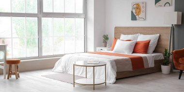 Büyük pencereli, yataklı ve masalı modern bir oda.