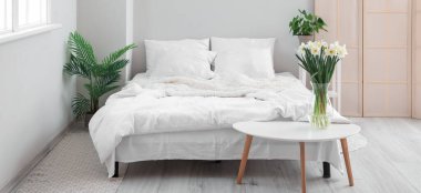 Bir buket nergisle aydınlık yatak odasının içinde. 