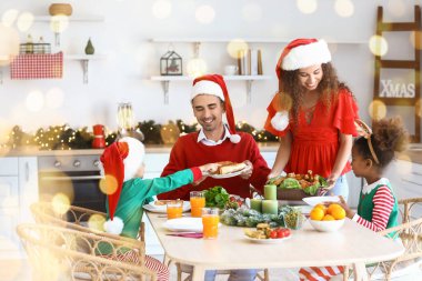 Mutlu bir aile mutfakta Noel yemeği yiyor.