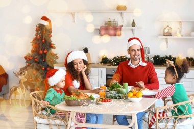 Mutlu bir aile mutfakta Noel yemeği yiyor.