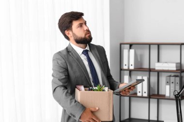 Ofisinde eşyalarını taşıyan kovulmuş genç bir adam.