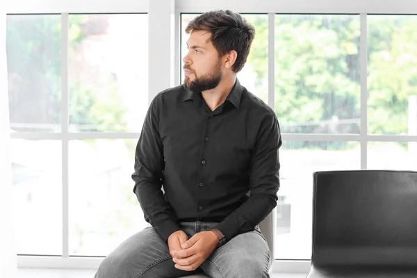 Fired young man sitting in office