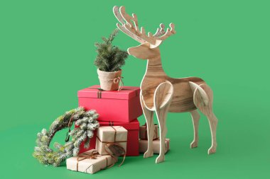 Tahta geyik Noel ağacı, çelenk ve yeşil arka planda hediyeler.