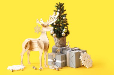 Tahta geyik Noel ağacı ve sarı arka planda hediyeler.