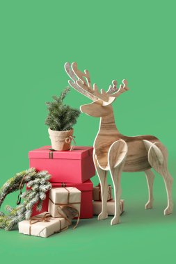 Tahta geyik Noel ağacı, çelenk ve yeşil arka planda hediyeler.